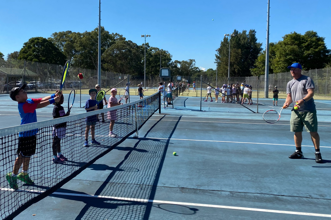 Tennis court with players and coaches on a sunny day
